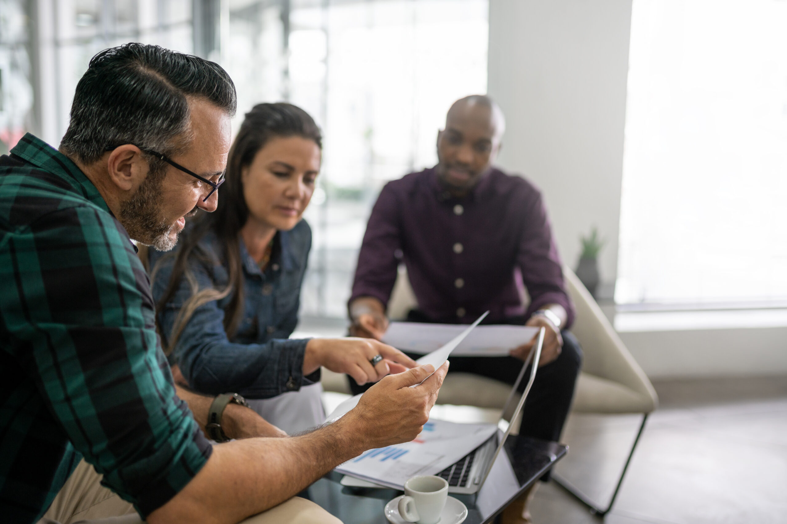 Three diverse businesspeople going over paperwork in an office lounge