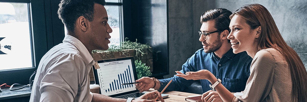 3 people reviewing business analytics on a laptop