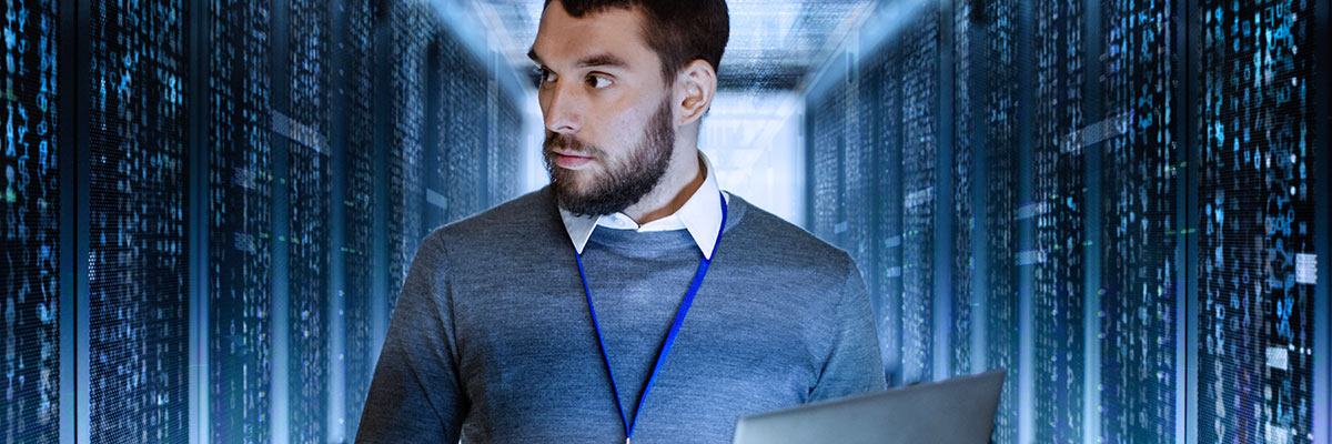 man working on a laptop in server room