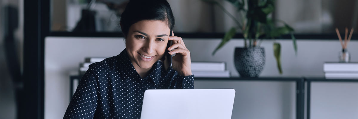 woman on her phone working on her laptop