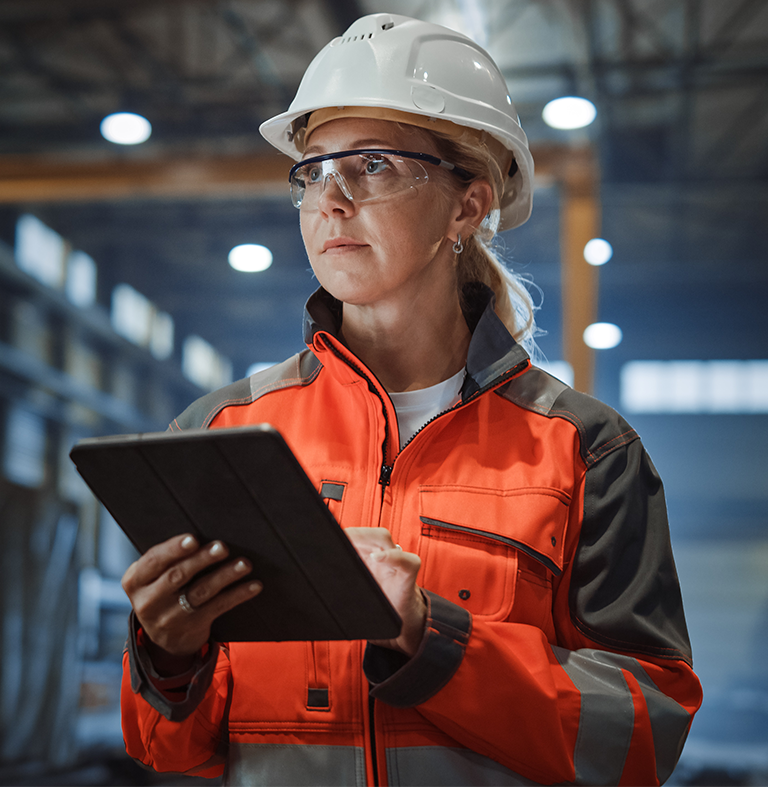 manufacturing-1 Woman wearing a hard hat in a manufacturing plant.